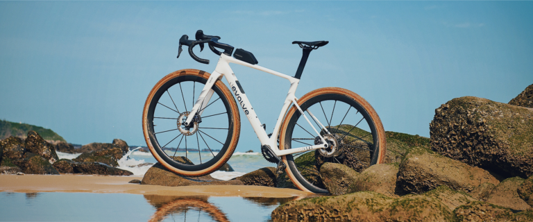 Evolve CIMA GR Sailfish Pearl apoiada em rochas na praia com pneus tan wall