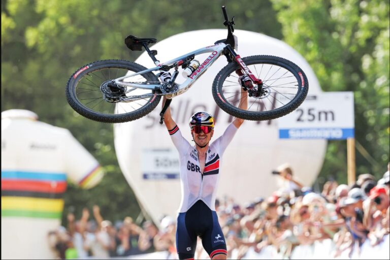 Tom Pidcock ergue a bicicleta ao comemorar o título mundial de XCO em Val di Sole